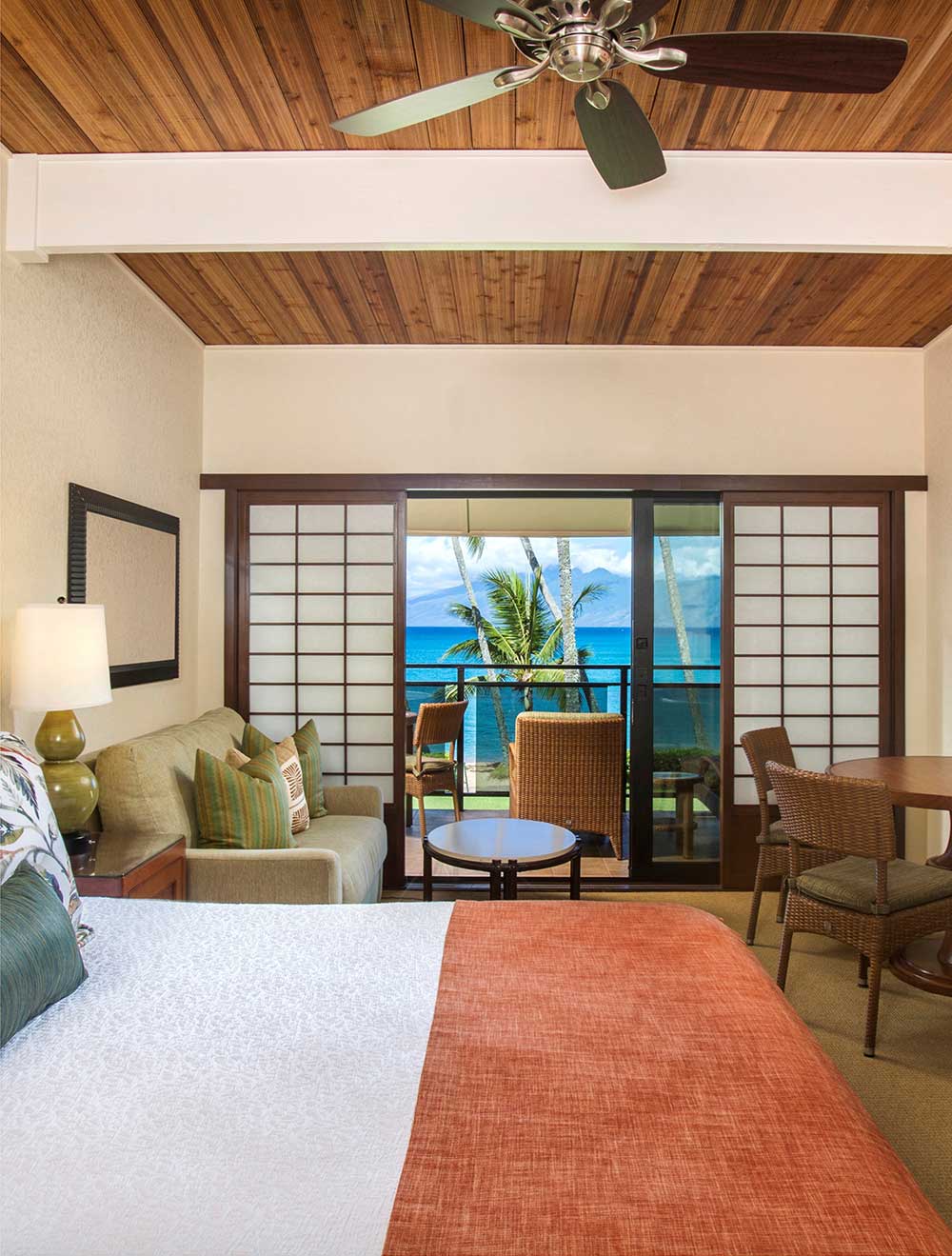 Beachfront studio with bed, seating area, and ocean view through sliding doors