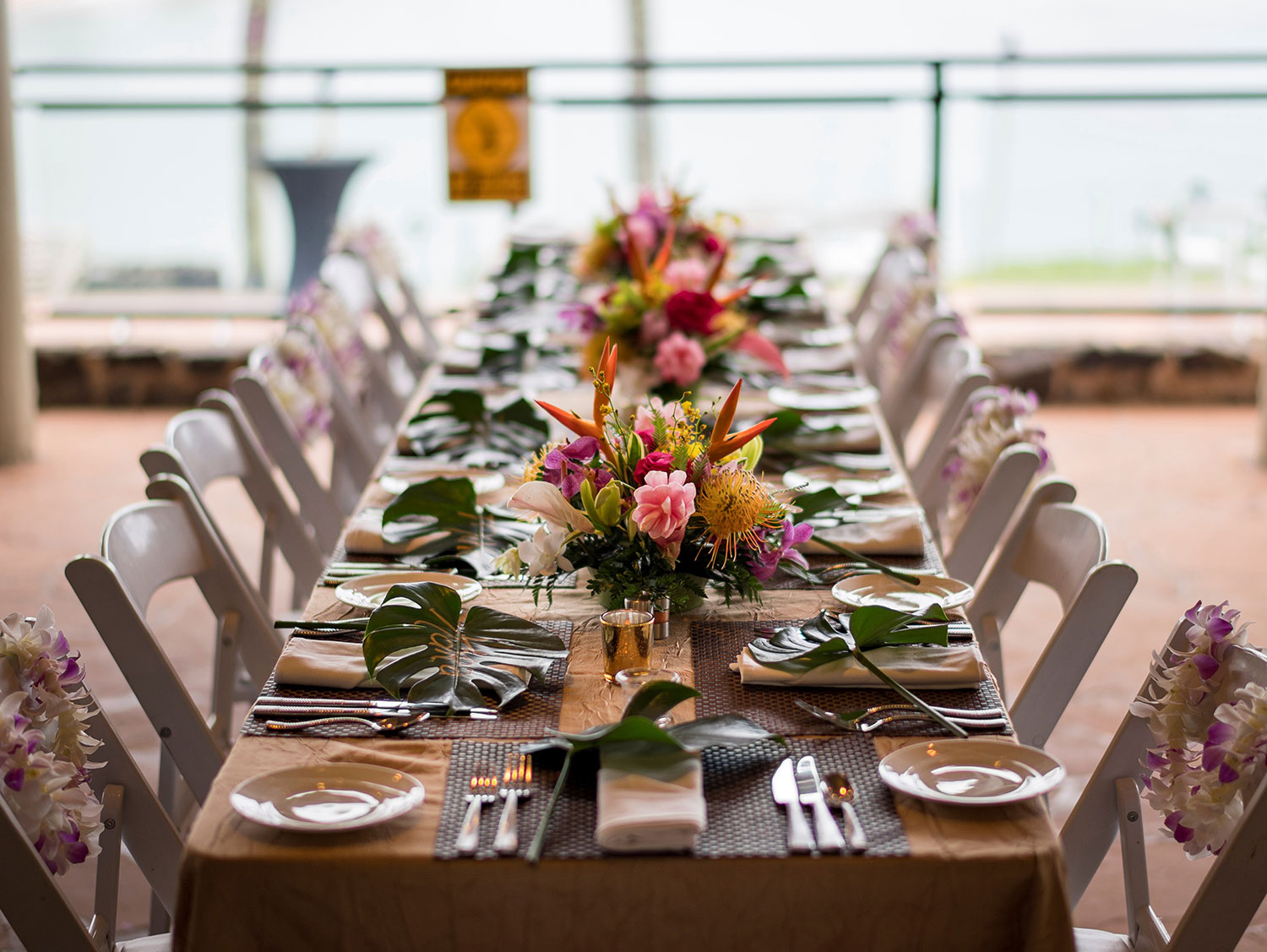 Beachfront event space with chairs and floral arrangements